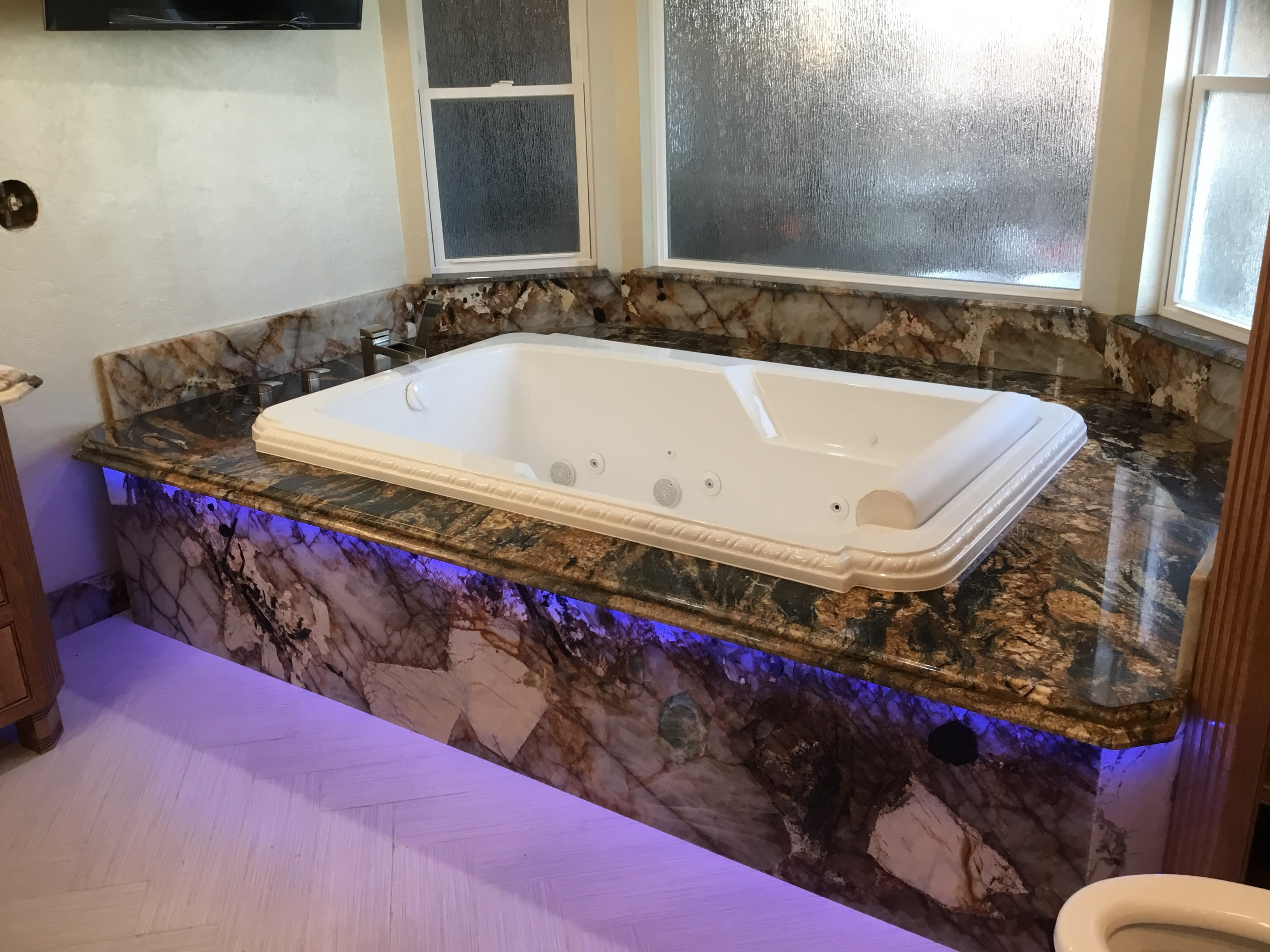 Luxury jacuzzi tub marble surround blue lighting — HCIC
