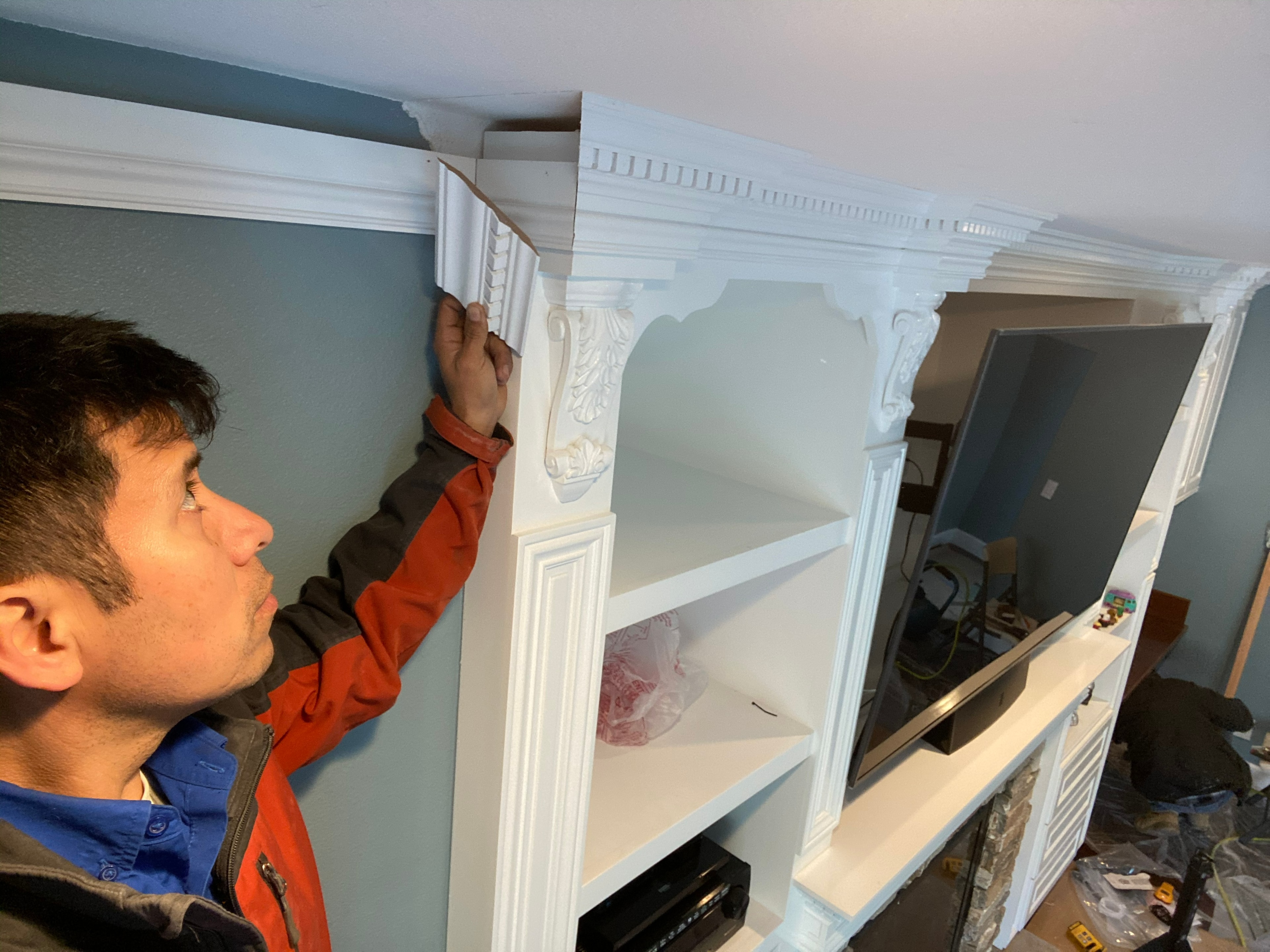Man installing white decorative shelving unit — HCIC