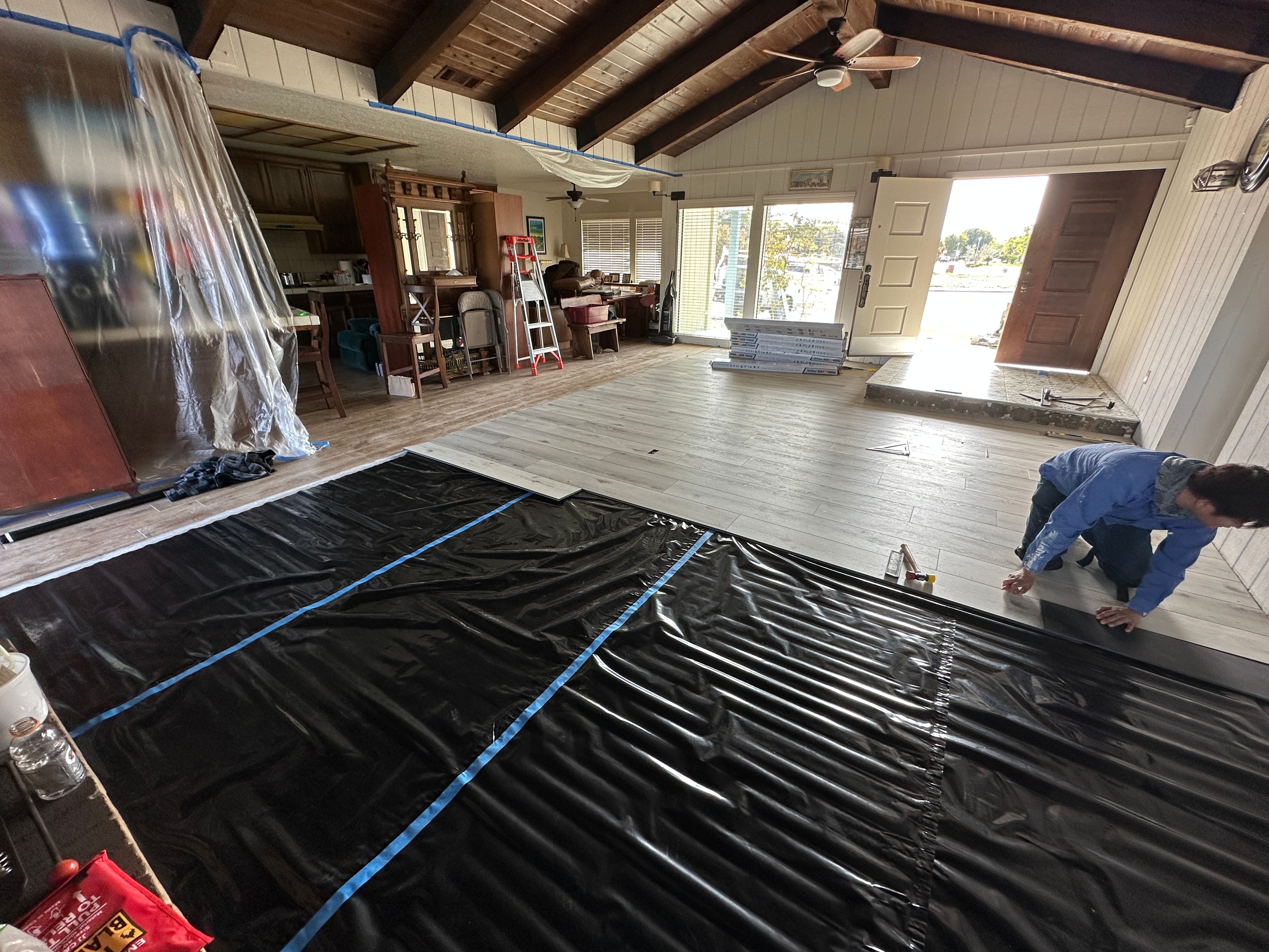 Worker installing black plastic flooring sheets — HCIC