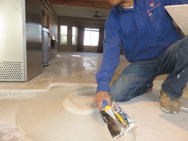Worker applying adhesive to floor — HCIC